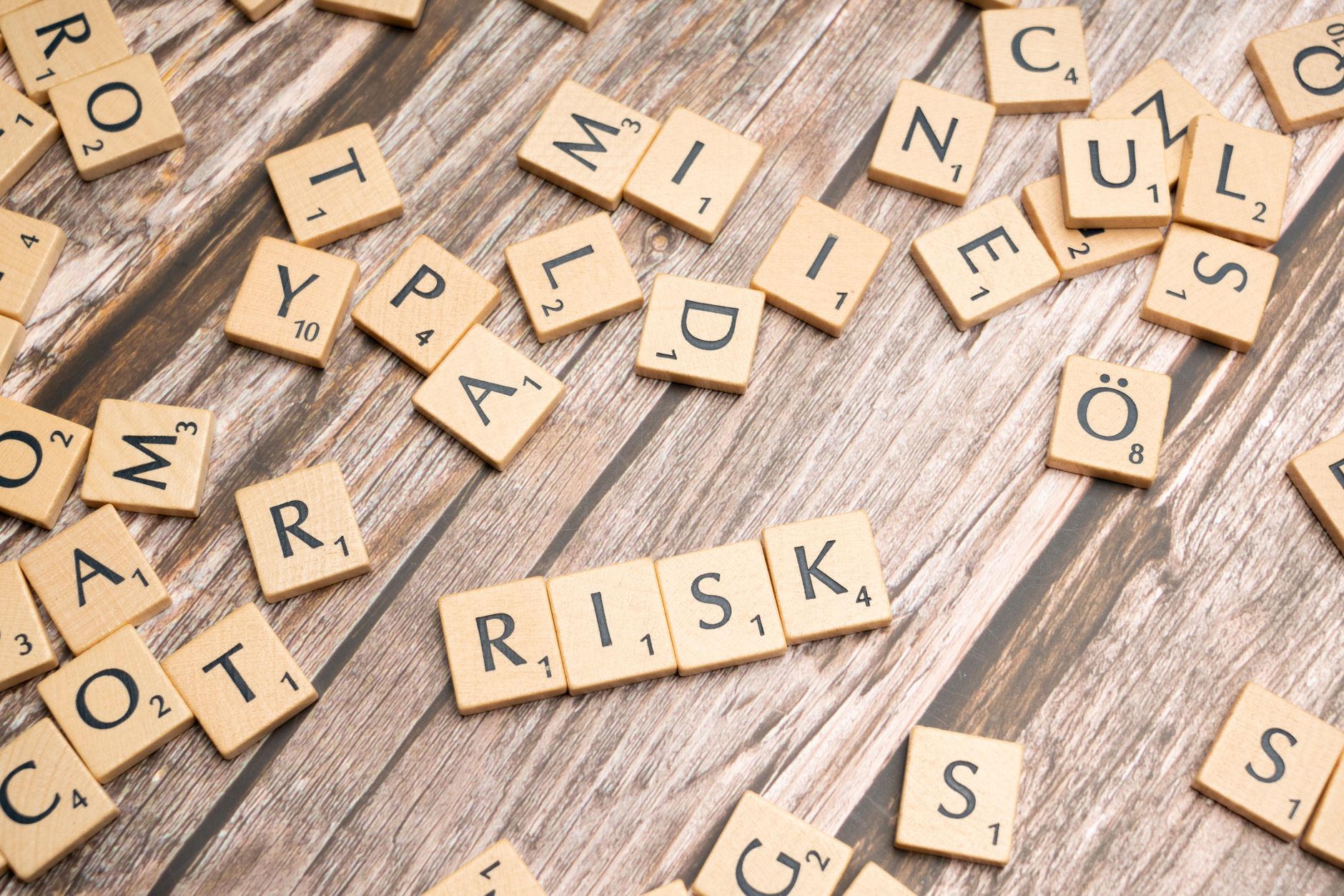 scrabble letters spelling risk on a wooden table